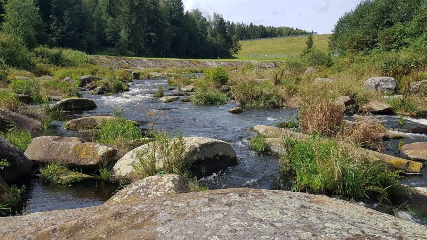 Pohled na slalomovou trať bez vody. V pozadí hráz přehrady Lipno.